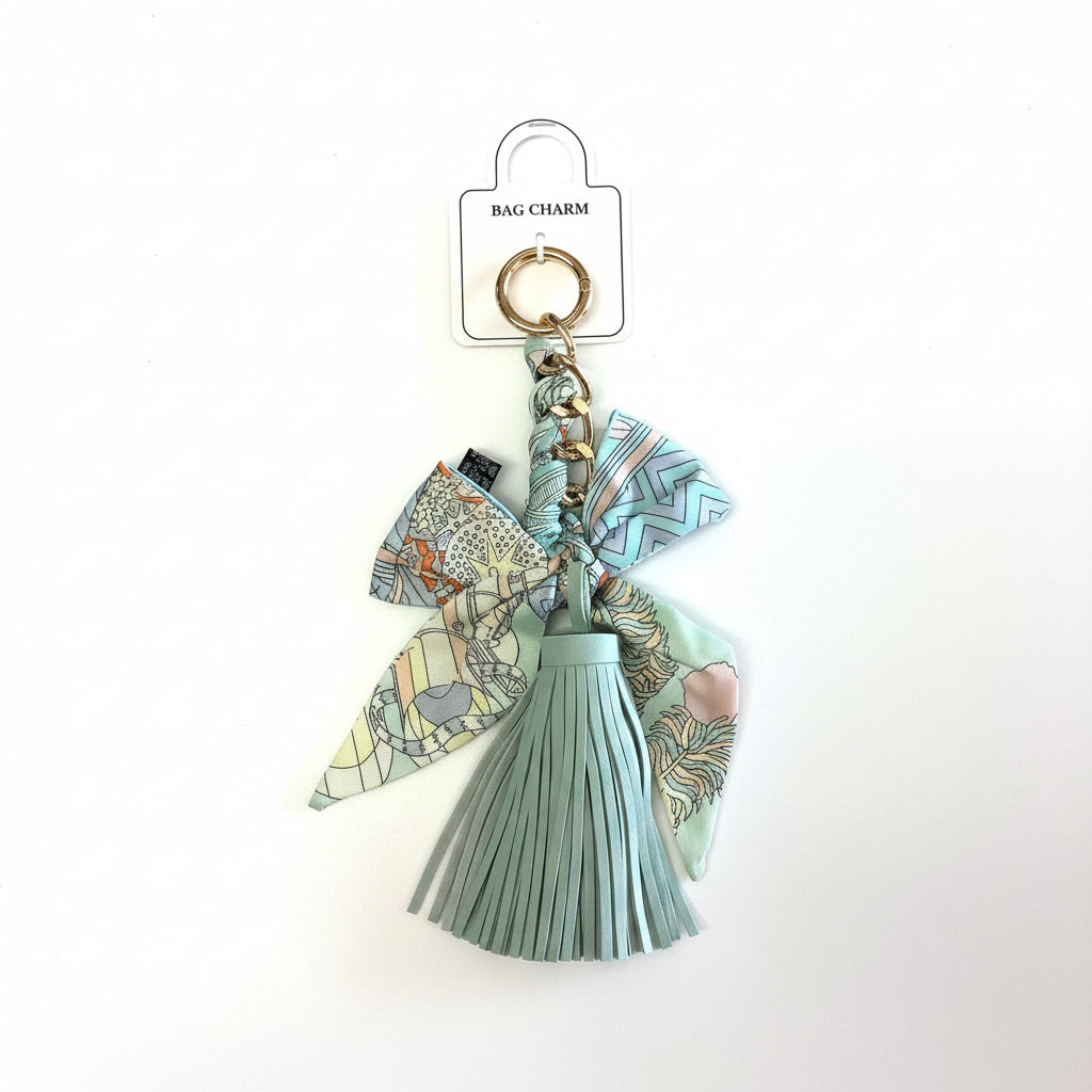 The Bow Tassel Bag Charm has a pale blue braided bow, two pastel patterned fabric bows, and a gold keyring. Available in small and medium sizes.