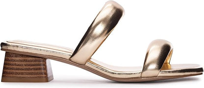The Alistair Heels - Metallic Gold have an open-toe design with two wide straps and a low stacked block heel. They feature a cushioned faux leather insole and a sleek metallic finish. Available sizes: 5-11 (US).