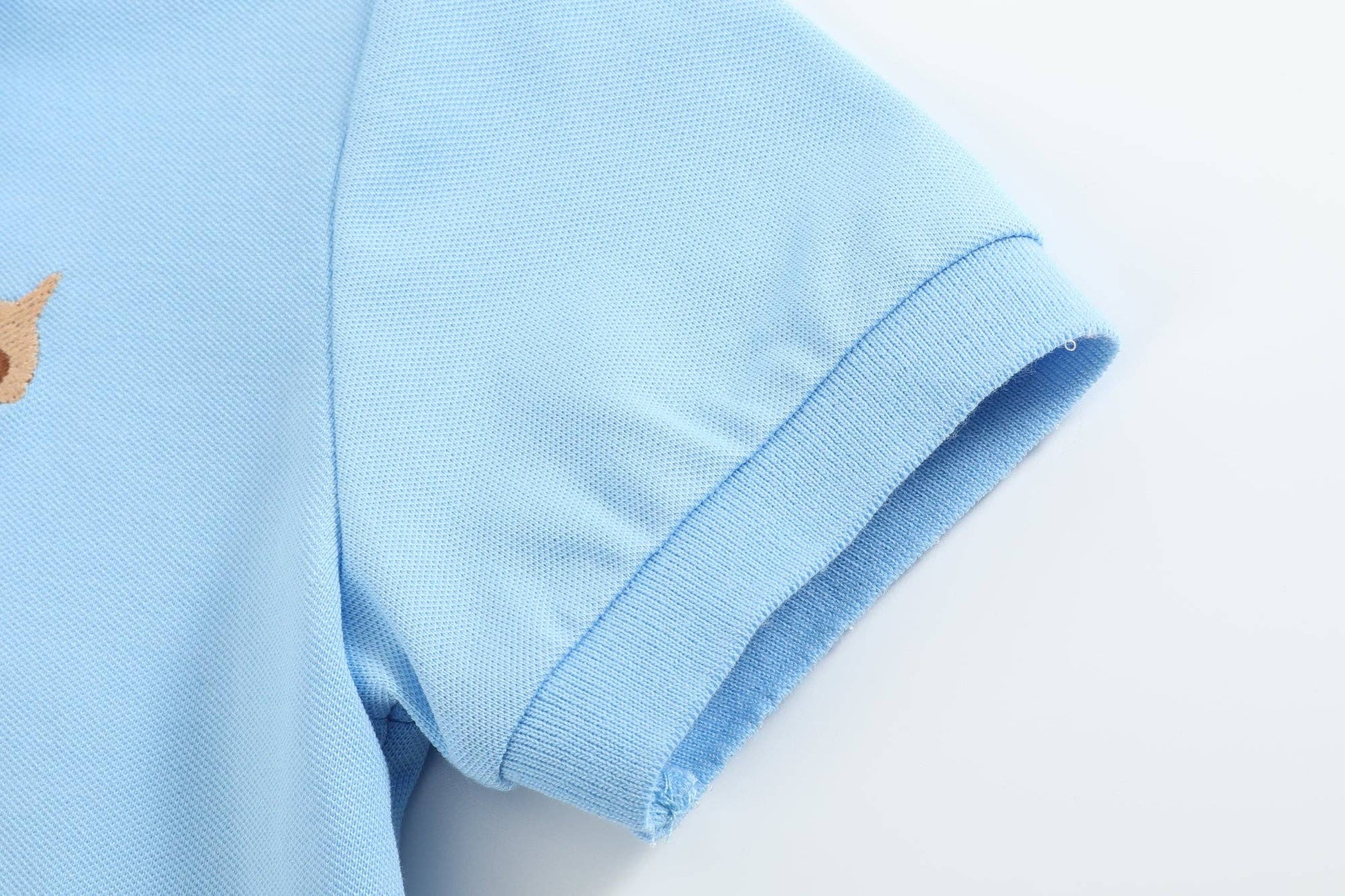 Close-up of Blue Puppy Polo Golf Shirt sleeve, showing stitching and textured fabric. Boys’ sizes: S, M, L, XL.