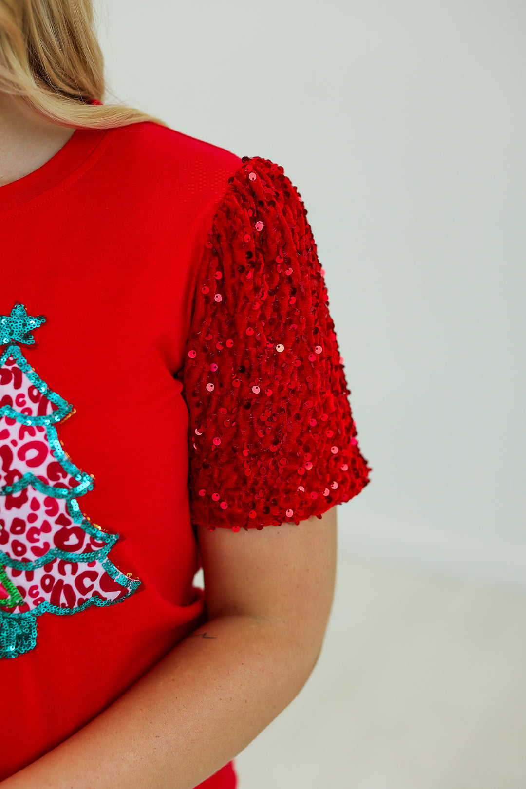 Trees with Sequin Short Sleeves Top, a relaxed-fit red shirt with sequined sleeves and a sequined leopard-print Christmas tree graphic.