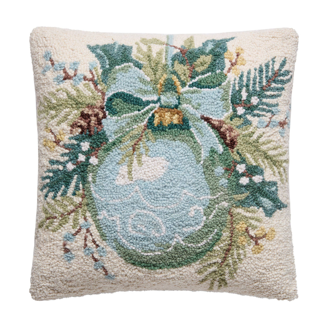 Ornament Square Hook Pillow with a blue ornament, green bow, pine branches, holly leaves, pinecones, and berries on a cream wool background. Available in multiple sizes.