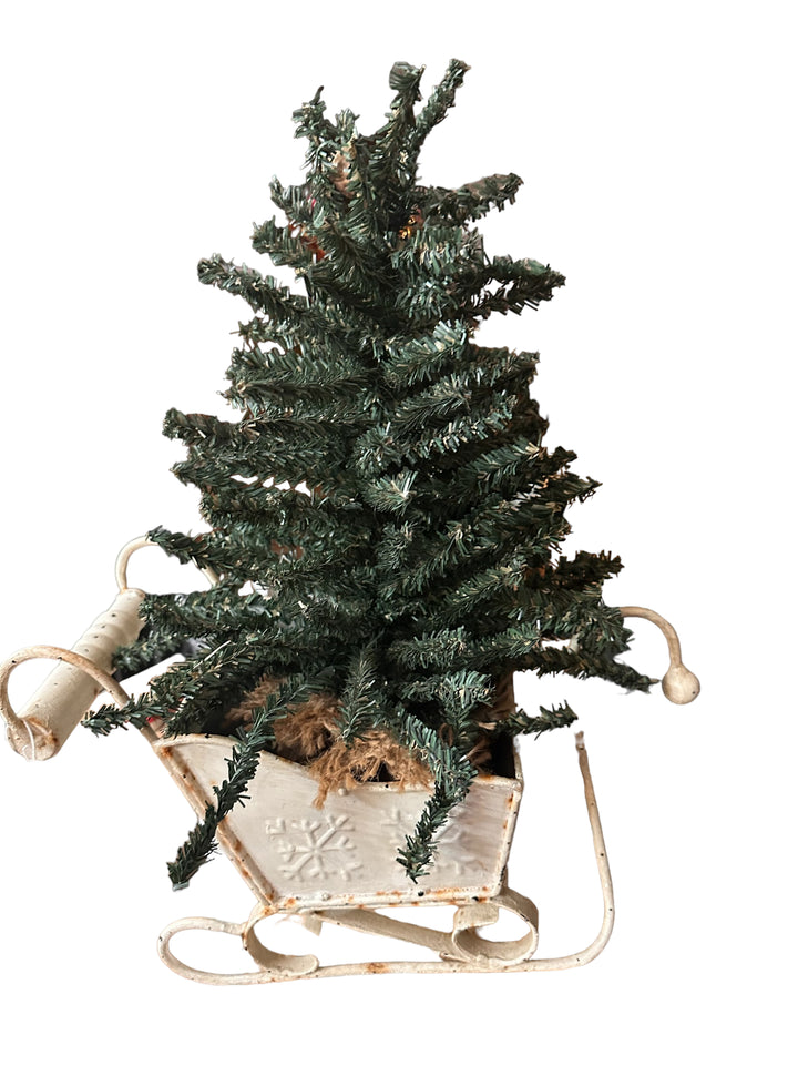 Small artificial Christmas tree in a vintage-style metal sleigh.