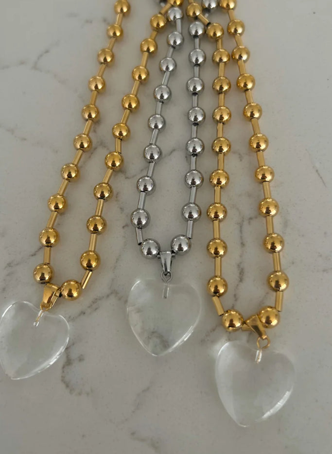 Three beaded Clear Heart Necklaces with large, translucent heart pendants. Two have gold beads; one has silver beads. Sizes available: Adjustable.