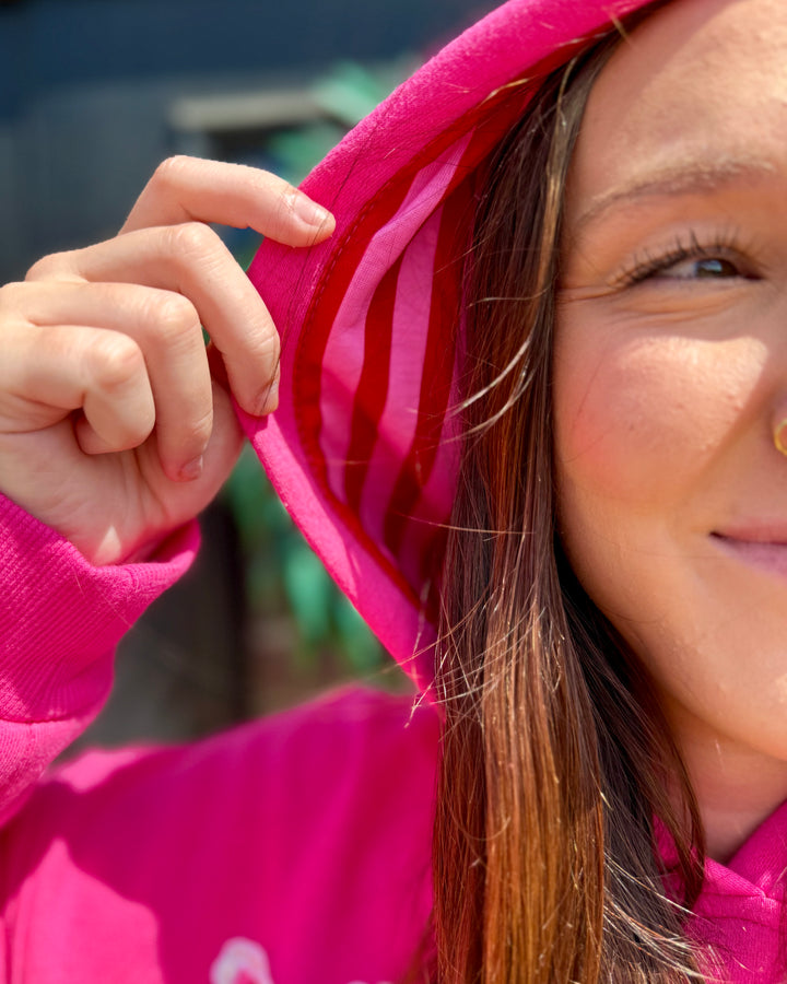 Bright pink Striped Scallop Merry Hoodie with red and white striped lining. Available in sizes XS-XL.