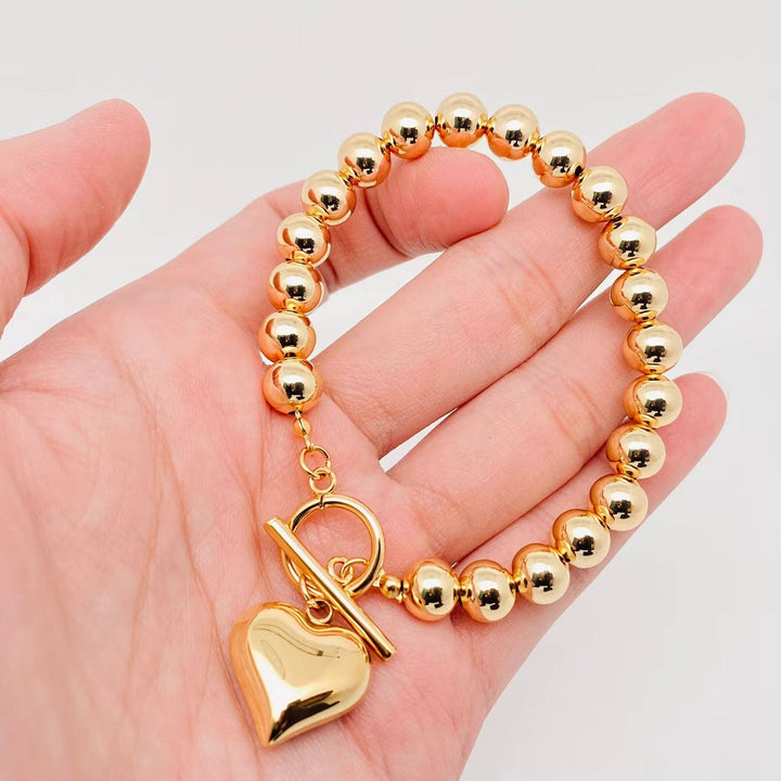 18K gold plated 8MM beads bracelet with heart charm and toggle clasp. Available in multiple sizes.