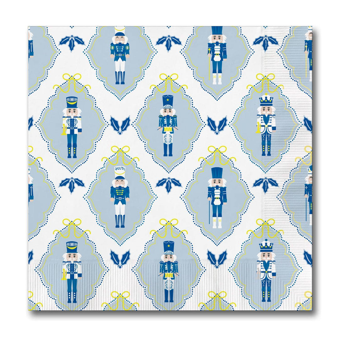 Square holiday cocktail napkins featuring a repeating pattern of blue and white nutcrackers, yellow bows, and blue holly icons.