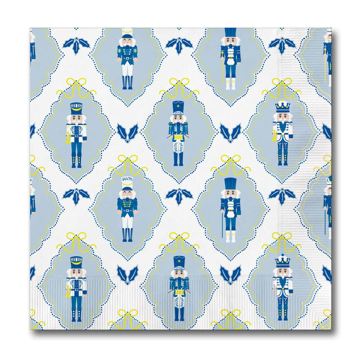 Square holiday cocktail napkins featuring a repeating pattern of blue and white nutcrackers, yellow bows, and blue holly icons.