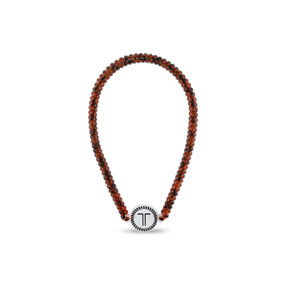 Beaded brown necklace with round white "T" pendant bordered in black. Available sizes: S, M, L.