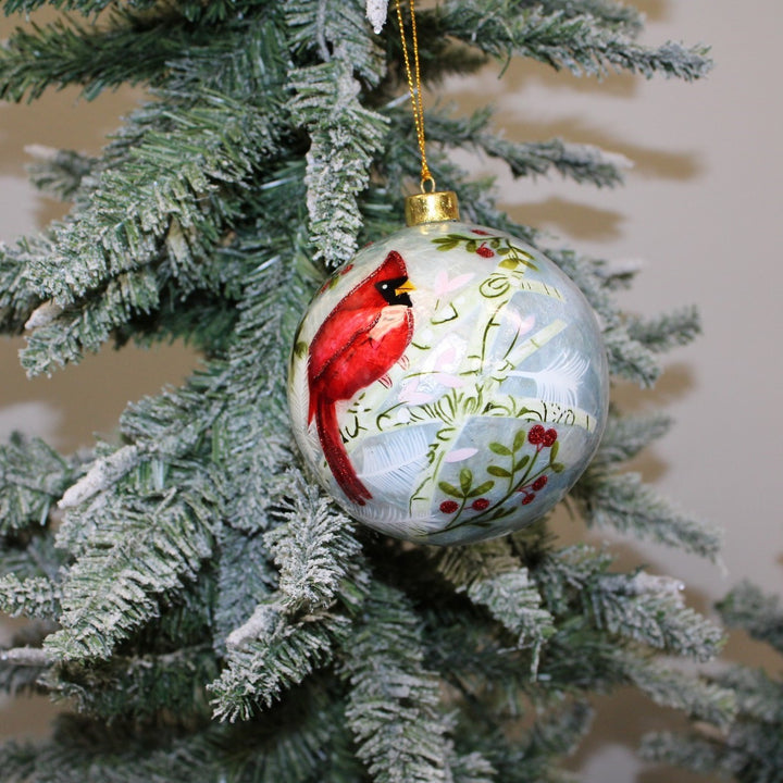 Cardinal Capiz Ball ornament featuring a painted red cardinal, holly berries, and winter foliage.