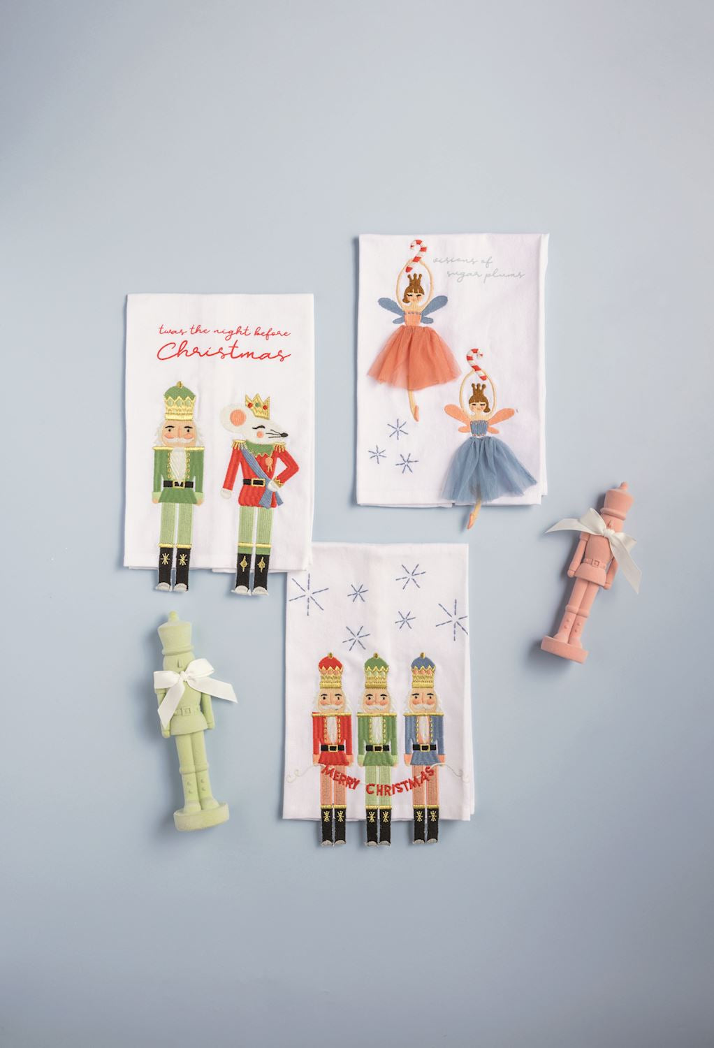 Three embroidered festive kitchen towels featuring nutcracker and sugar plum fairy designs.