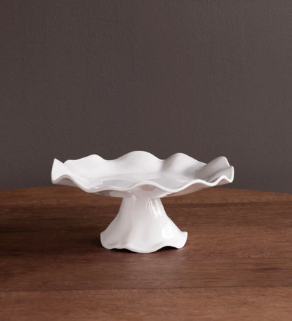 White ceramic cake stand with wavy edge, available in small and large sizes.
