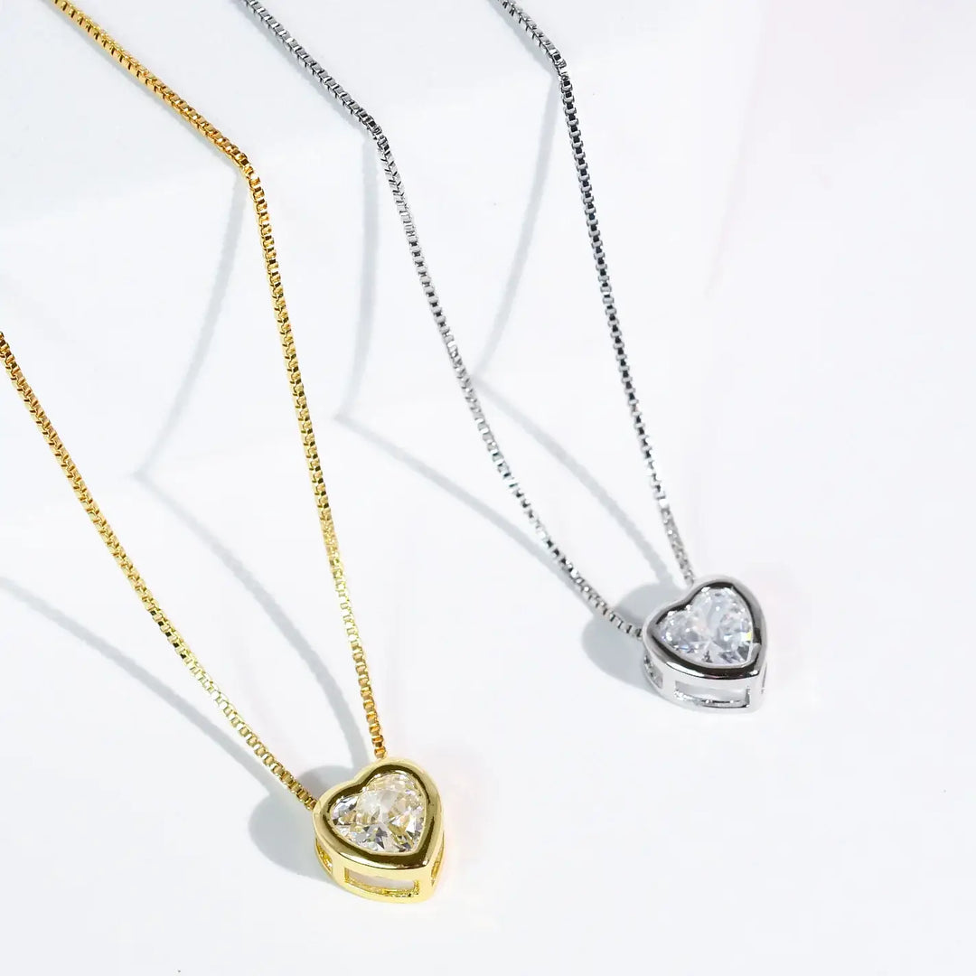 The Tiny Love Necklace: Silver features a heart-shaped clear crystal pendant. Available sizes: S, M, L.