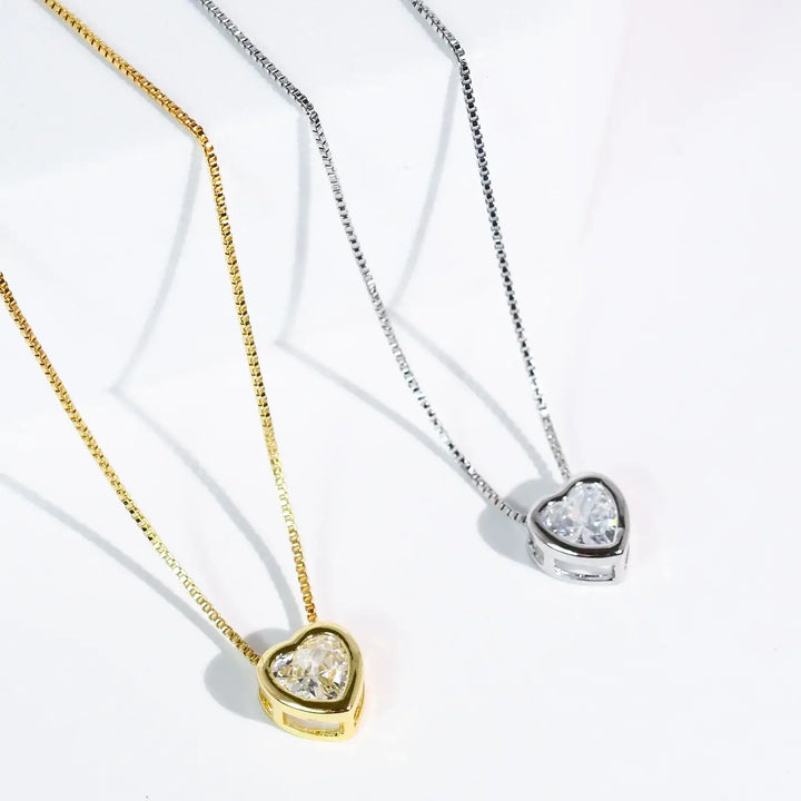 The Tiny Love Necklace: Silver features a heart-shaped clear crystal pendant. Available sizes: S, M, L.