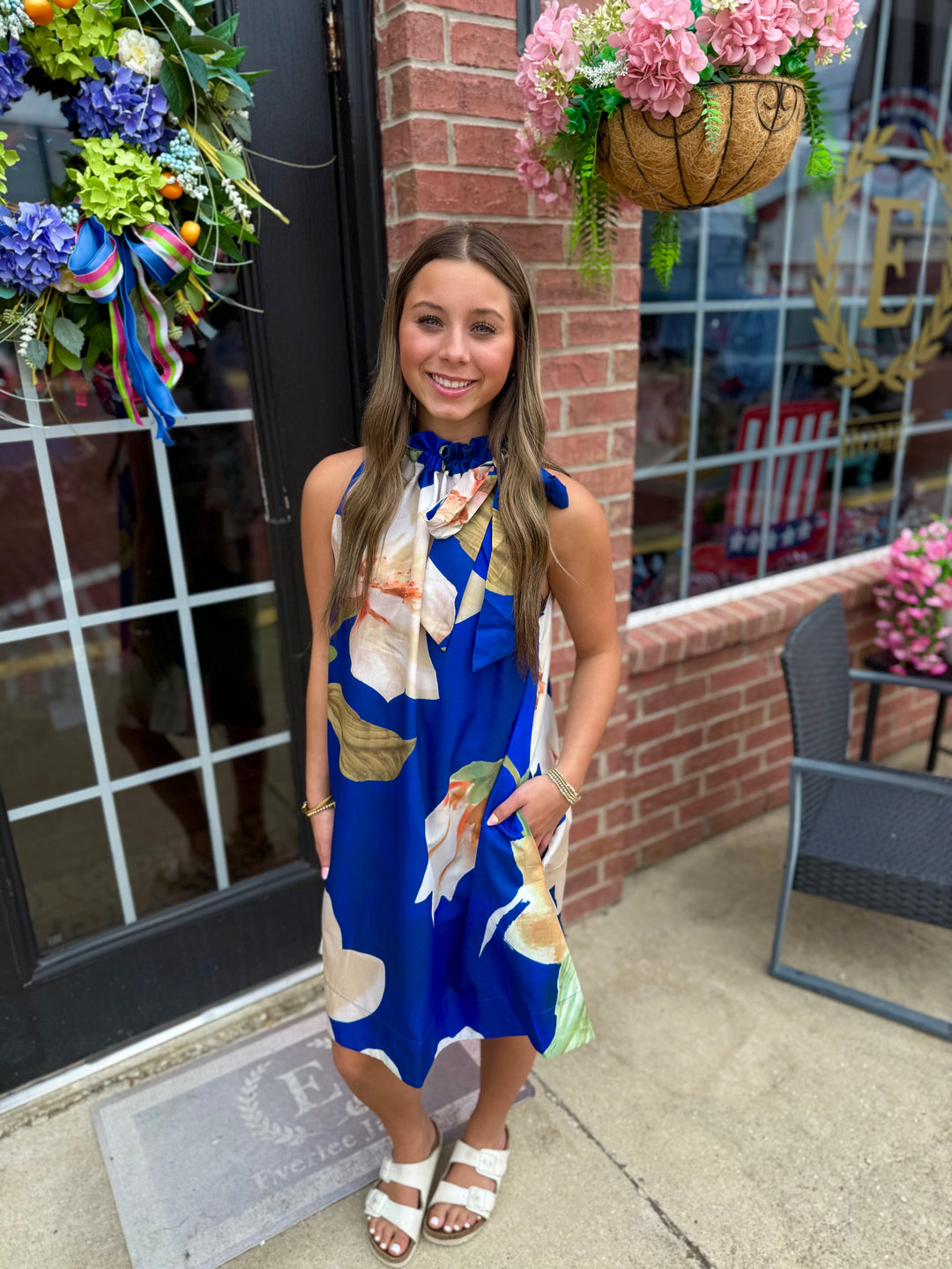 Royal Blue Floral Ruffle Tie-Neck Sleeveless Dress, available in sizes XS-XL. Features ruffles and a floral print.
