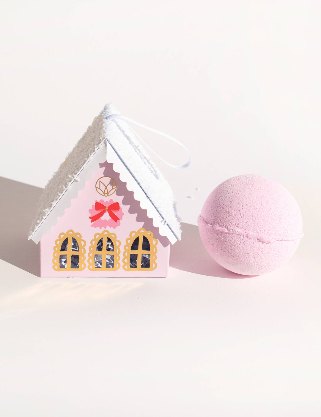 Pink Christmas Village Pink House box with a white roof and pink spherical holiday bath balm.
