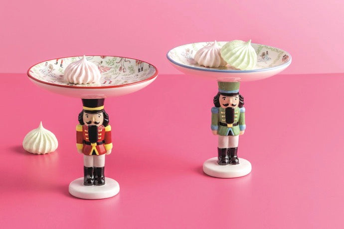 Two Nutcracker candy dish pedestal bowls with nutcracker bases and patterned bowls.
