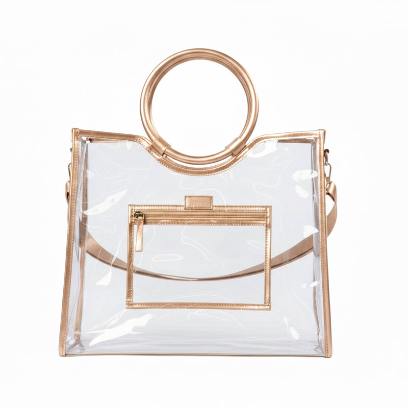 Clear PVC tote with gold trim, round gold handles, detachable matching strap, and front zippered pocket. Available in multiple sizes.
