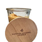 A glass jar labeled "Pumpkin Caramel Drizzle Candle" with a wooden lid, containing orange-brown soybean wax for a long-lasting burn. Available in sizes: small, medium, and large.