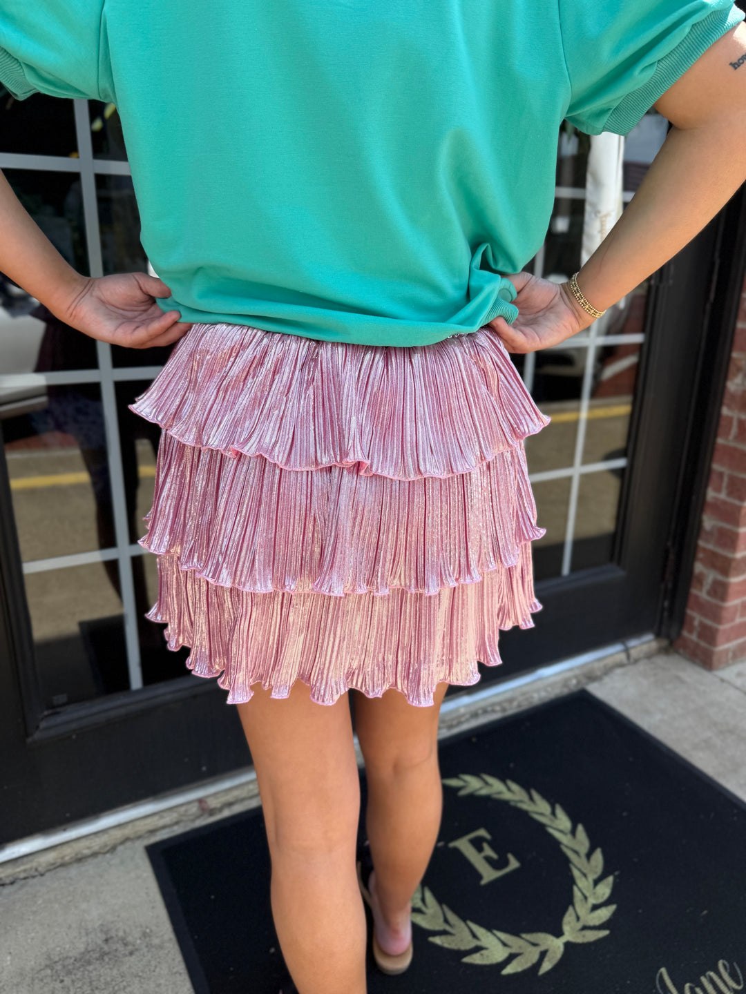 Metallic pink three-tiered shimmer ruffle skirt with elastic waistband. Available in all sizes.