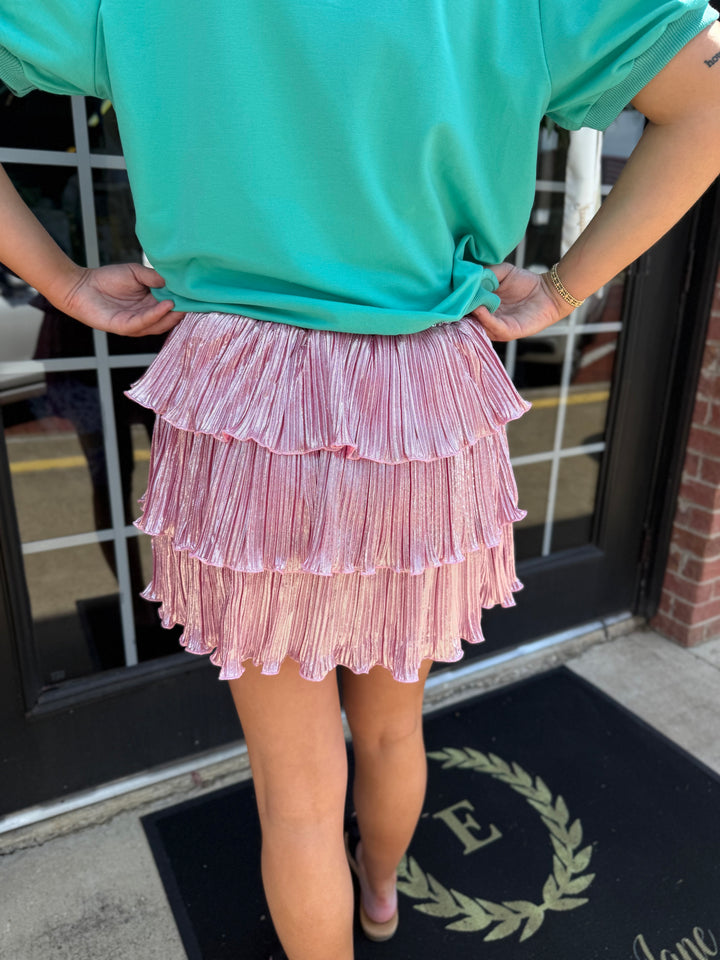 Metallic pink three-tiered shimmer ruffle skirt with elastic waistband. Available in all sizes.