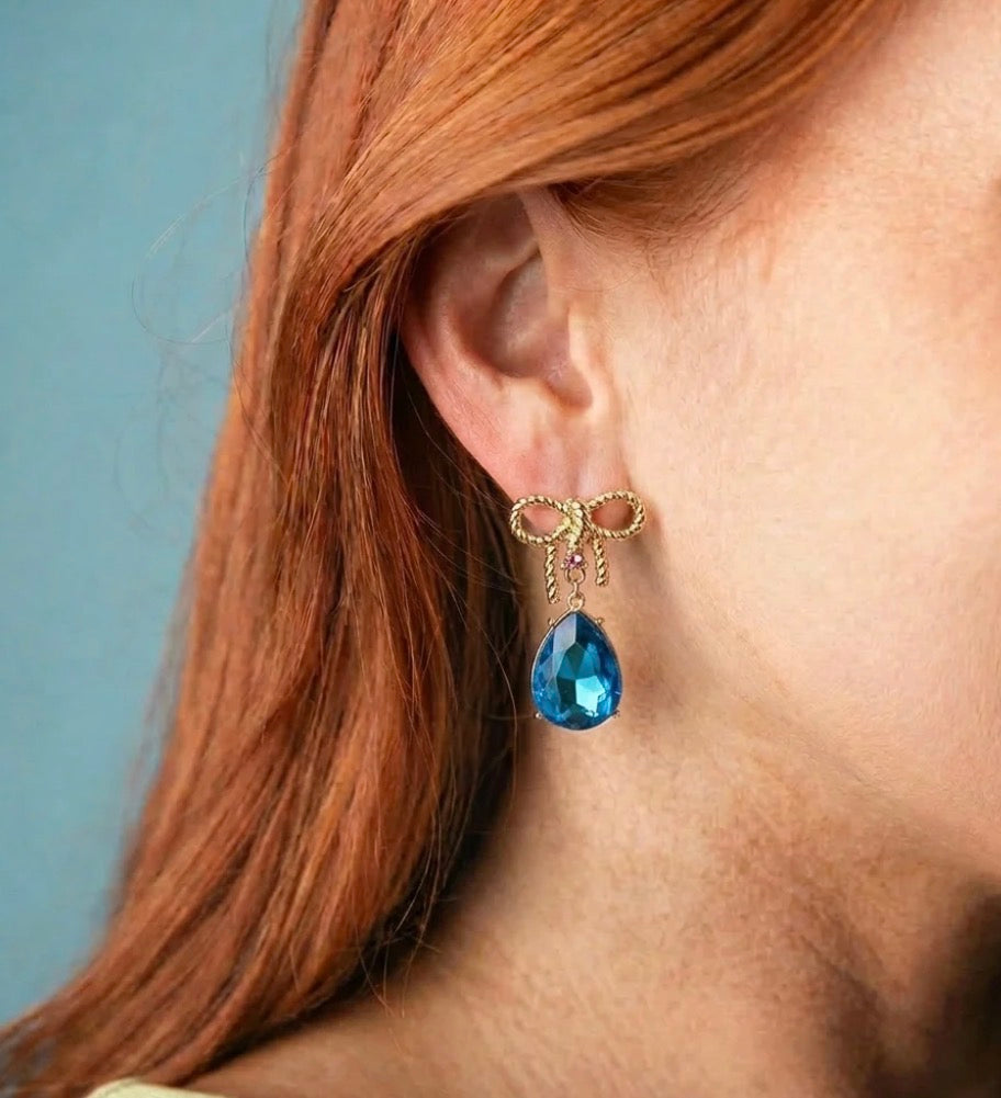 Gold Bow Teardrop Earrings featuring elegant gold bows and large blue teardrop gems. Available in small, medium, and large sizes.
