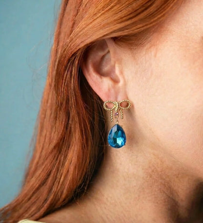 Gold Bow Teardrop Earrings featuring elegant gold bows and large blue teardrop gems. Available in small, medium, and large sizes.