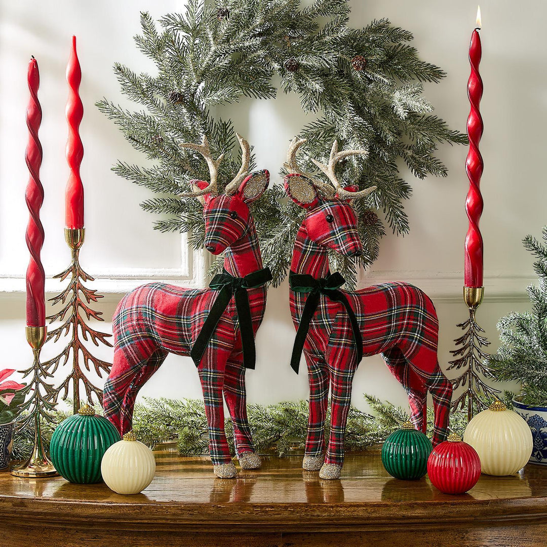 Two tartan reindeer figurines in red and green fabric with black velvet ribbons.