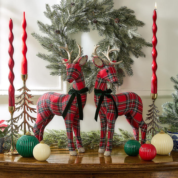 Two tartan reindeer figurines in red and green fabric with black velvet ribbons.