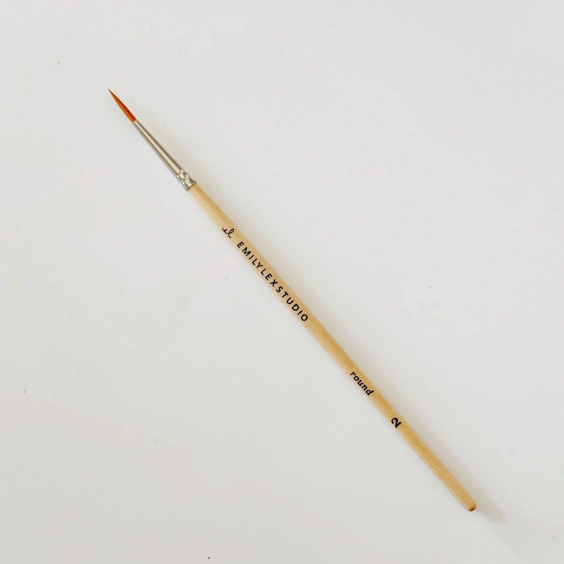 Thin round paintbrush with synthetic taklon bristles, wooden handle marked "EMILYEK STUDIO round 2." Sizes: 2, 4, 6, 8, 10.