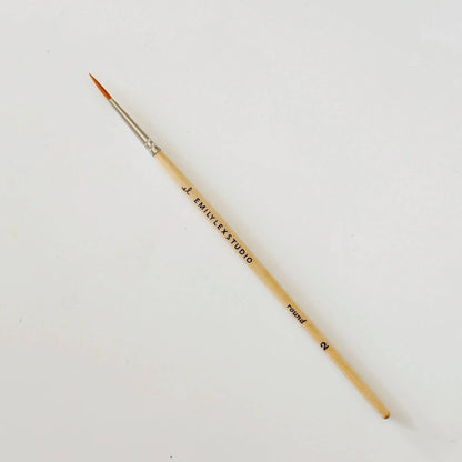 Thin round paintbrush with synthetic taklon bristles, wooden handle marked "EMILYEK STUDIO round 2." Sizes: 2, 4, 6, 8, 10.