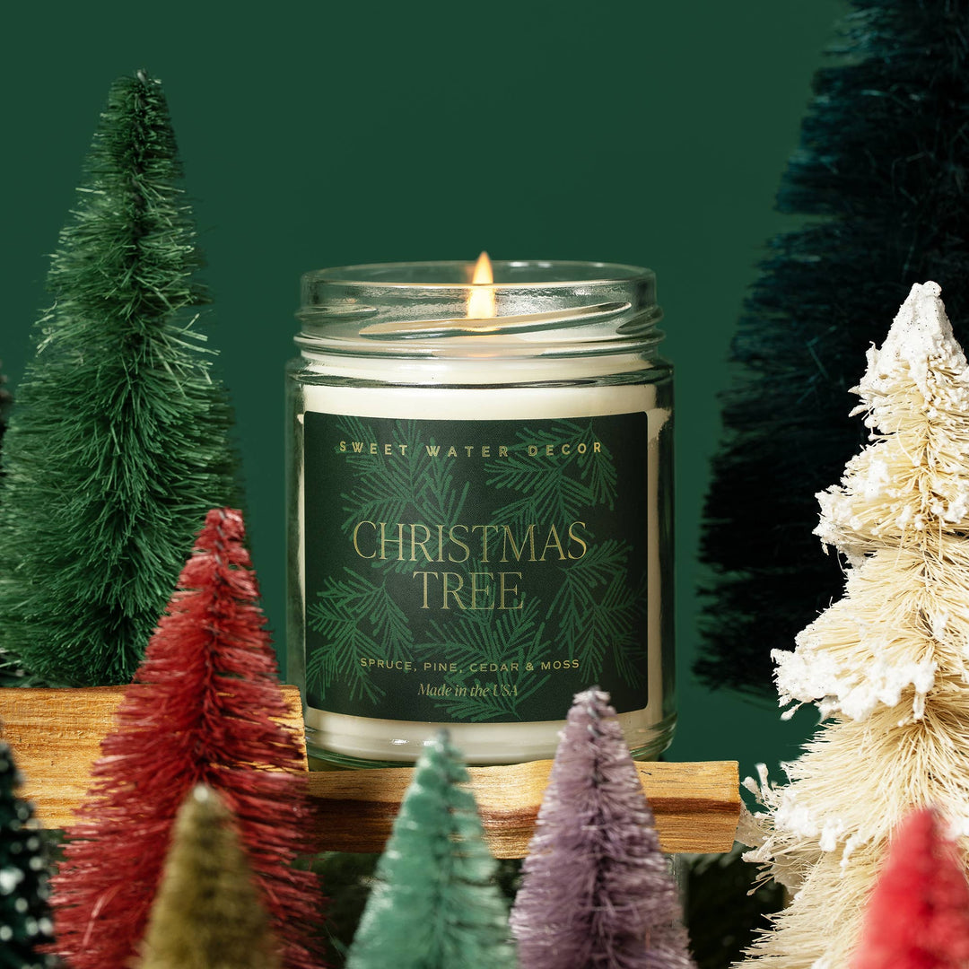 9 oz Christmas Tree soy candle in a glass jar with a lit wick.