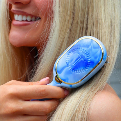 Tide & True Mini Boar Brush, a compact blue and white travel brush with a circular design and letter “T” in the center. Available in mini size.