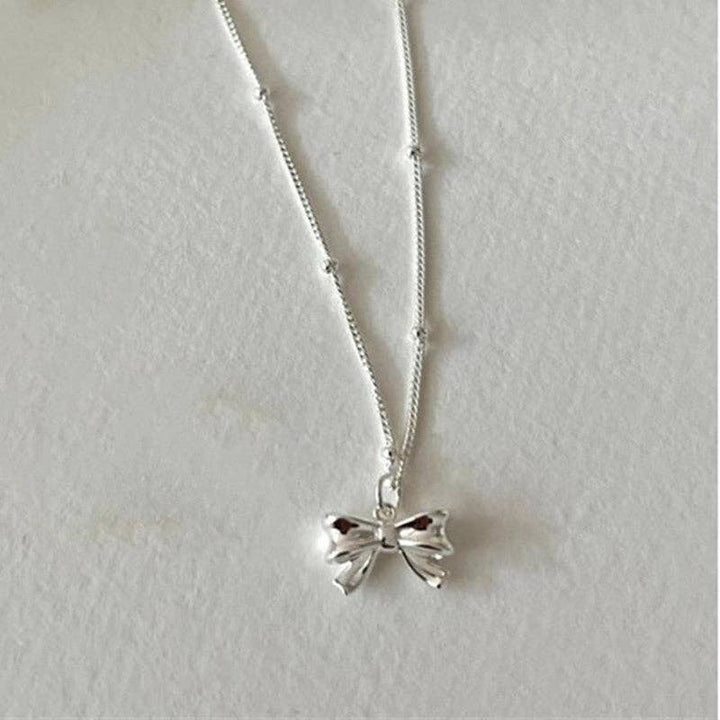 Dainty Bow Tie Bowknot Charm Necklace in 925 Sterling Silver with a shiny bow pendant; available in various sizes.