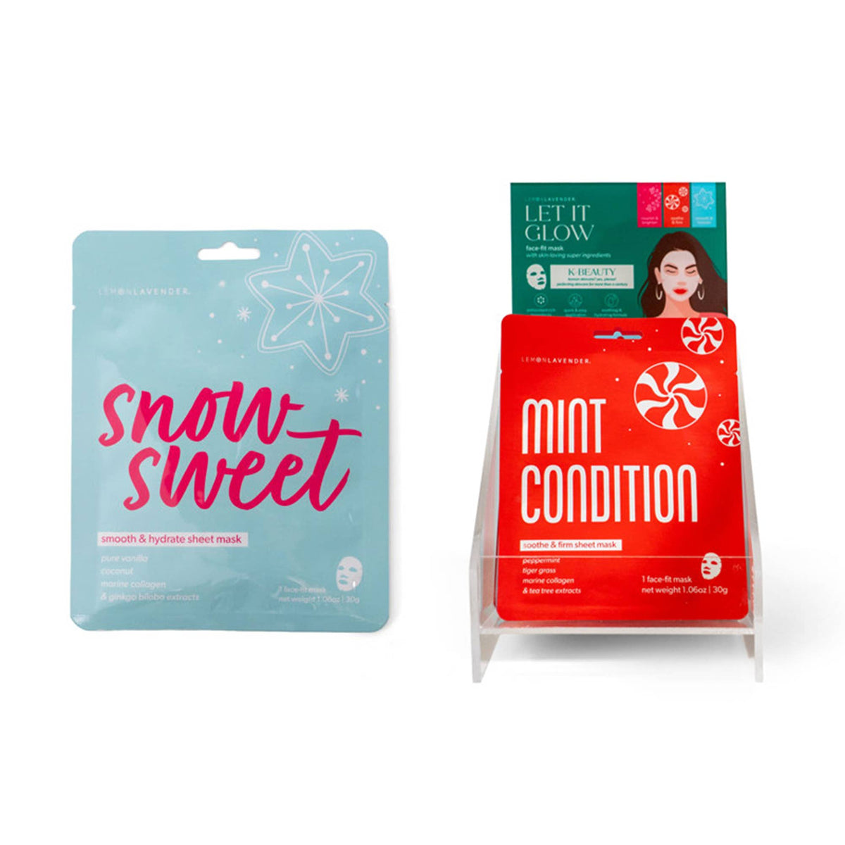 Two single-use Lemon Lavender Let It Glow Holiday Face Masks are shown, one in a blue “Snow Sweet” package with stars and one in a red “Mint Condition” package. Available in individual single-use size.