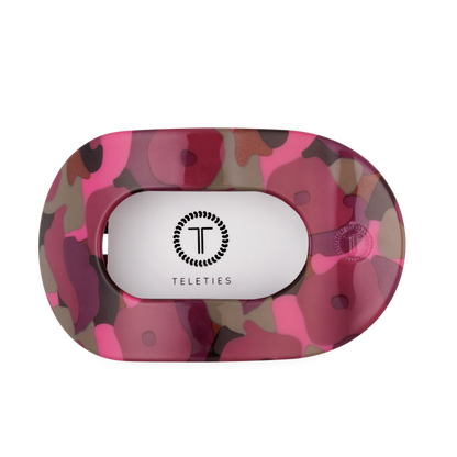 The Garden Glam Large Flat Round Hair Clip has an oval holder with a pink, maroon, and olive camouflage pattern and a white center featuring the TELETIES logo and name in black. Available in large size.
