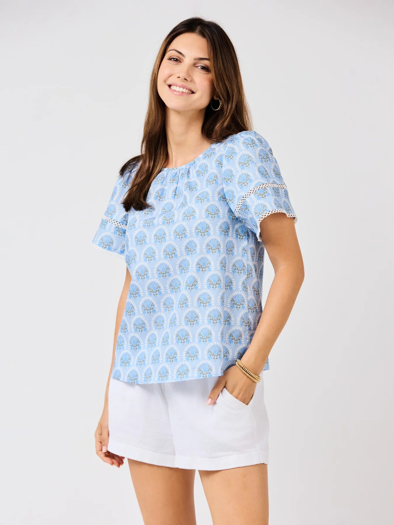 Tabby Sunshower Flora Blue Top with white eyelet detail and flutter sleeves. Available in sizes XS-XL.
