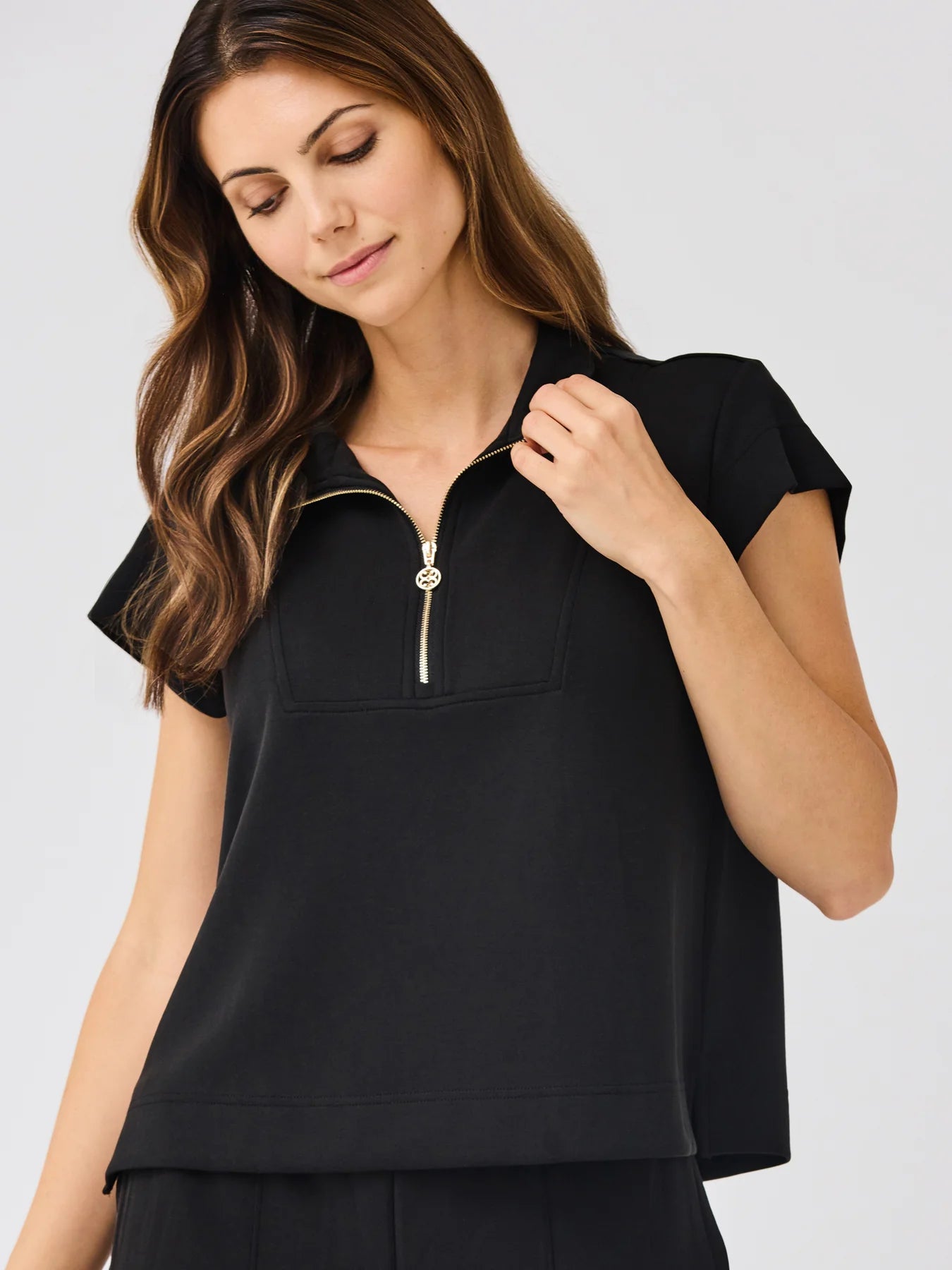 Stephie Top in black, short sleeves, ultra-soft modal blend, zippered pop collar. Available in sizes XS–XL.