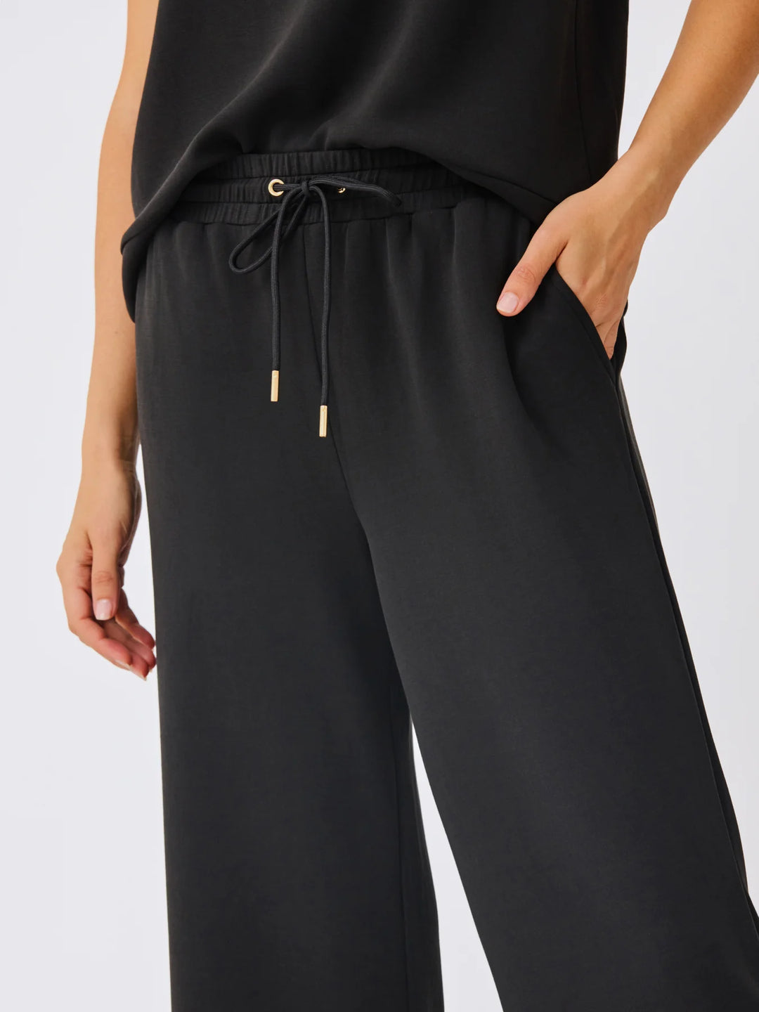 Sabrina Cropped Pants in black with wide legs, elastic waistband, gold-tipped drawstrings. Sizes: XS-XL.