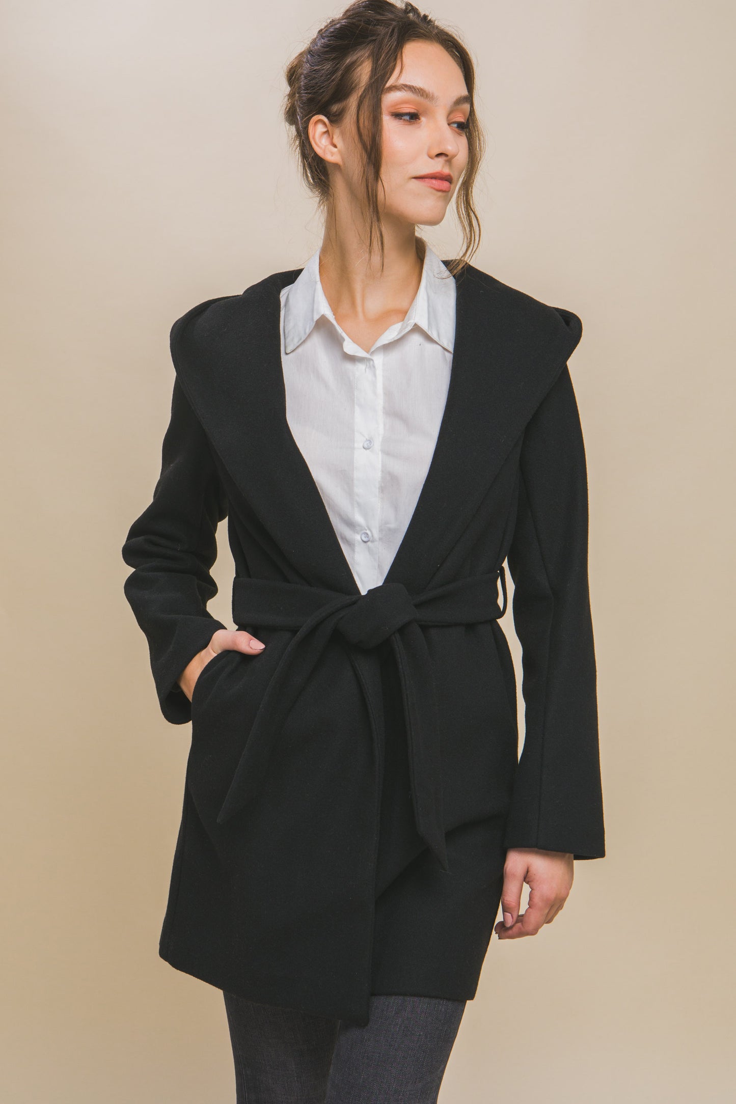 The Fleece Belted Hoodie Coat in black is cozy and stylish, featuring a unique design that combines comfort with elegance. Available in sizes XS to XL.