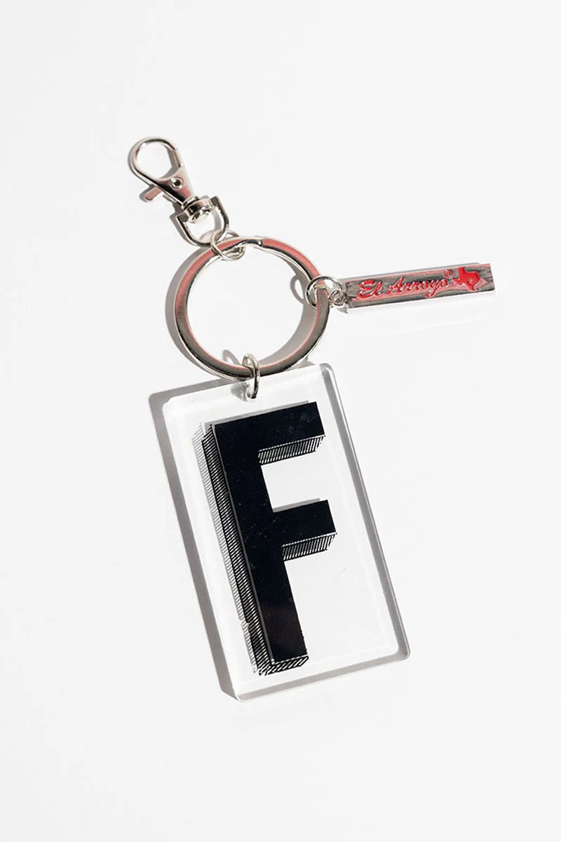 Clear acrylic keychain with bold black "F" in El Arroyo style; includes small metallic tag. Available in one size.