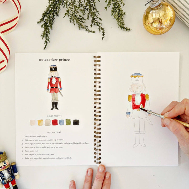 Nutcracker watercolor workbook featuring a finished illustration, color palette, instructions, and an unfinished sketch with a paintbrush. Available in all standard sizes.