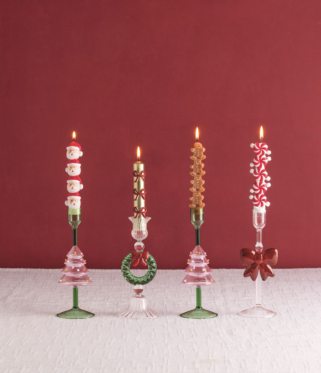Four lighted Christmas Mini Taper Candles in decorative glass candle holders.