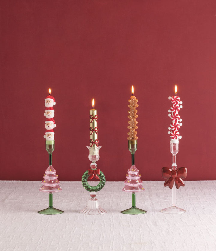 Four lighted Christmas Mini Taper Candles in decorative glass candle holders.