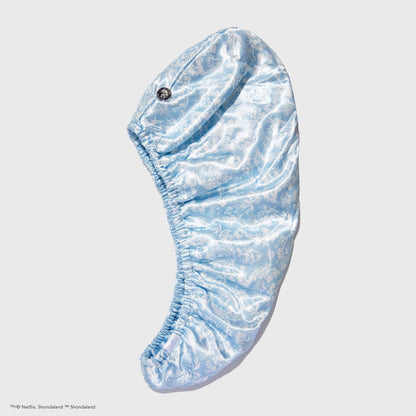 Light blue satin hair towel with subtle floral print and elastic edges; available in one size; reduces frizz.