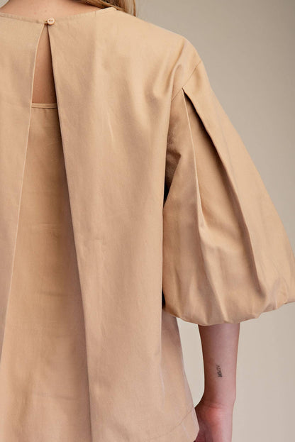 Taupe round neck puff sleeve top with fine pleats, lightweight fabric, and keyhole back. Available in sizes XS-XL.