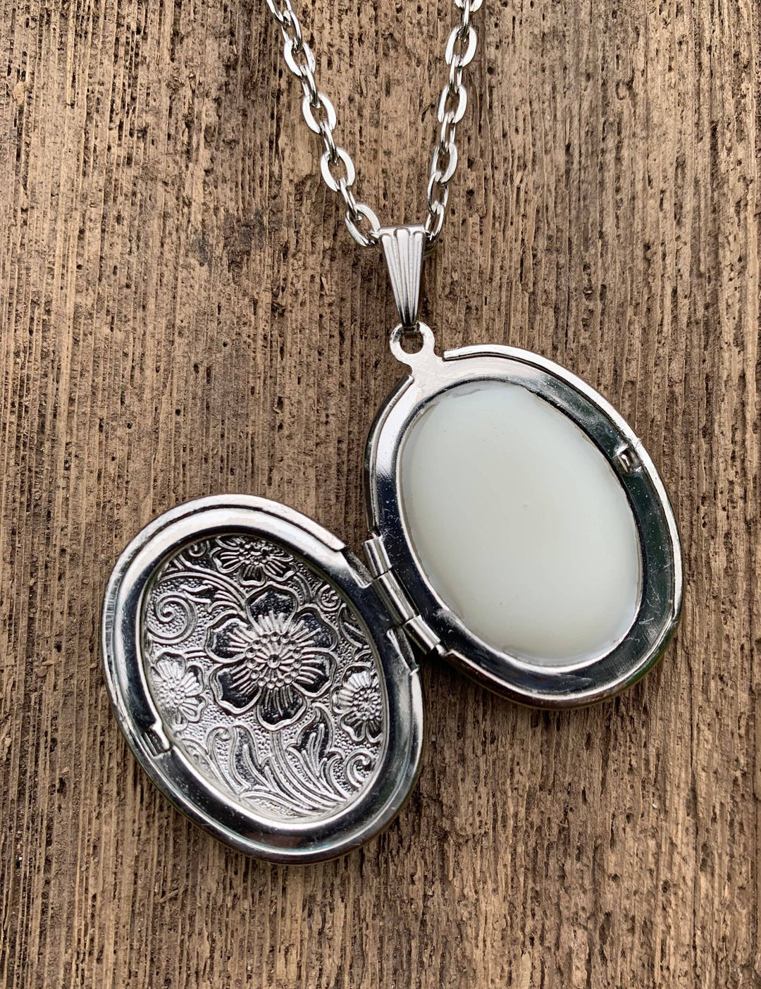 Antiqued silver locket with solid gardenia perfume, oval and floral engraved; available in small and medium sizes.