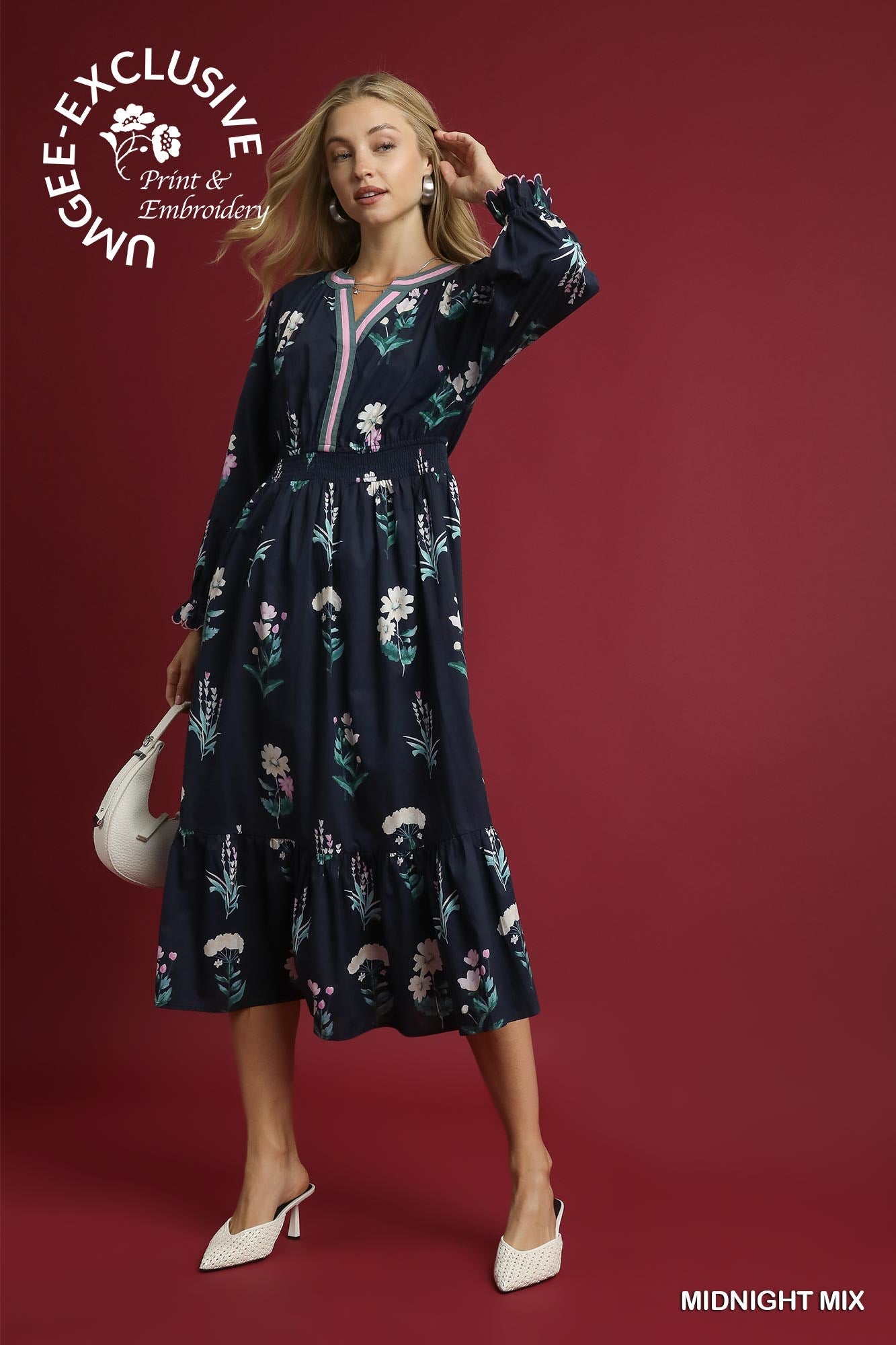 Navy blue, long-sleeved maxi dress with embroidered florals. Available sizes: XS–XL. Text: “UNGEE EXCLUSIVE.”.