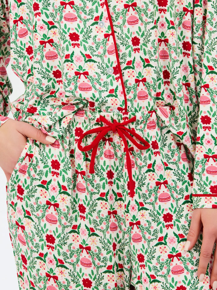 Charlotte Trimmed with Joy button-down pajama set in a white, green, and red ornament and floral print with red piping and a red drawstring waist. Available in various sizes.