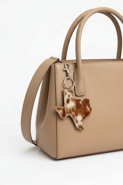 Beige genuine leather shoulder handbag with Texas-shaped brown and white cowhide keychain clip. Sizes: Small, Medium, Large.