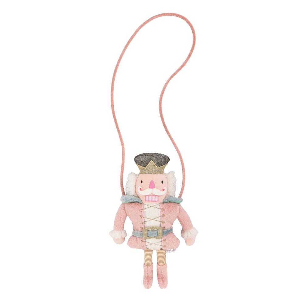 Pink Nutcracker-shaped plush purse with glittery crown, belt, and long strap.